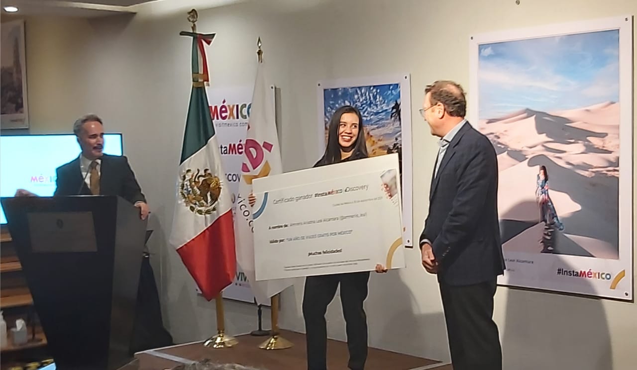 Romina Ramírez (en representación de la ganadora del premio #InstaMexico), recibe el premio de manos de Marcos Achar, presidente de Visit México